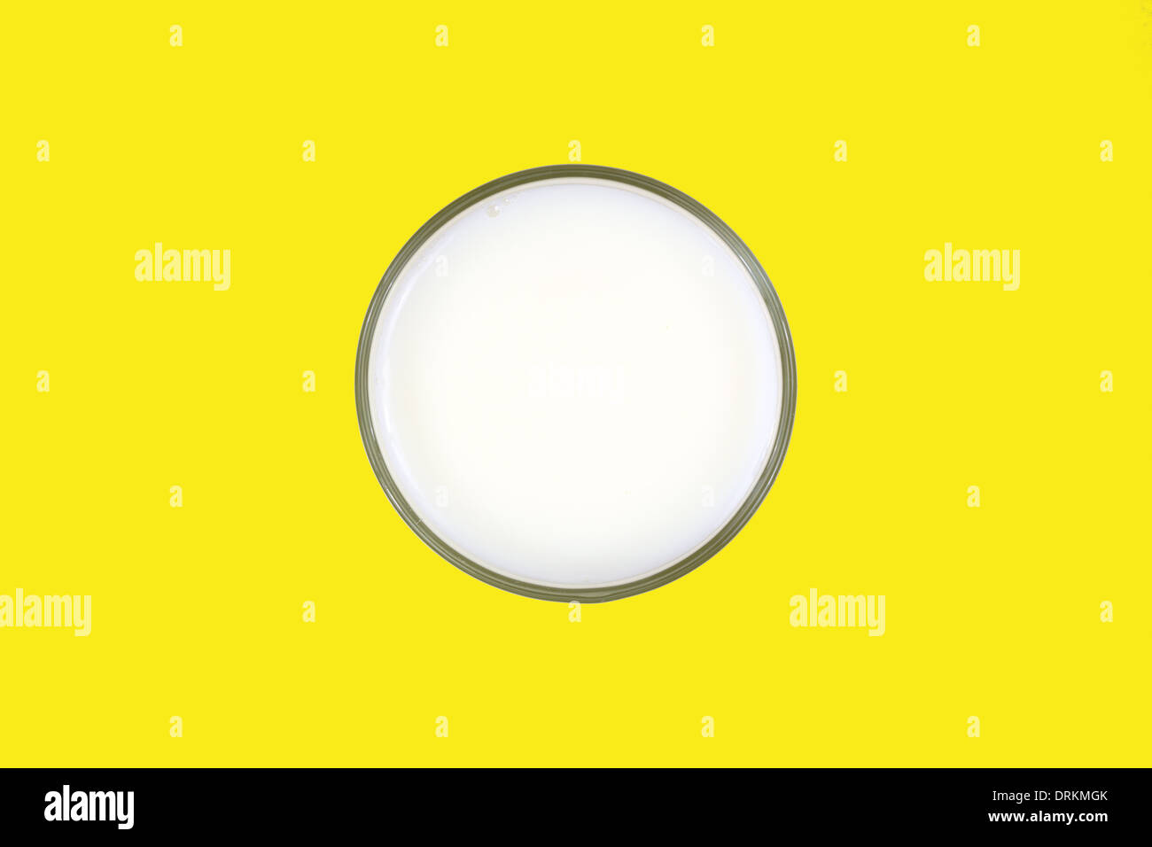 Top view of a glass of skim milk on a bright yellow background. Stock Photo
