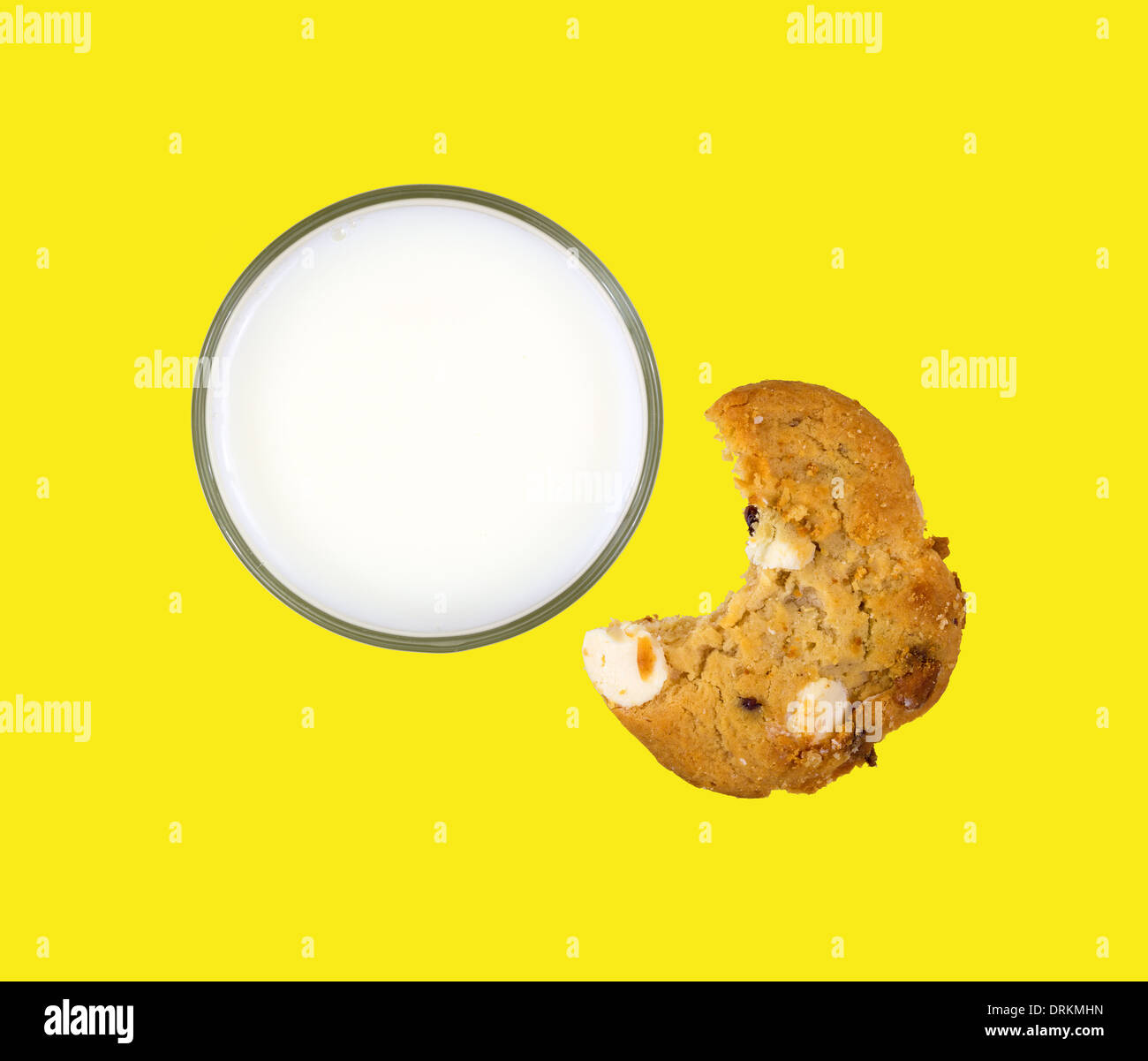 Top view of a glass of skim milk with a partially eaten cookie on a bright yellow background. Stock Photo