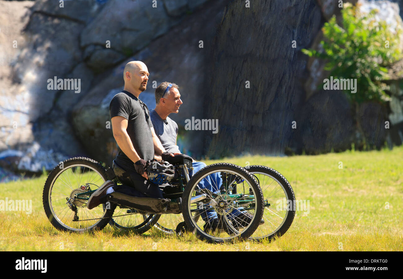 Two men with spinal cord injuries riding on off-road hand cycles Stock Photo