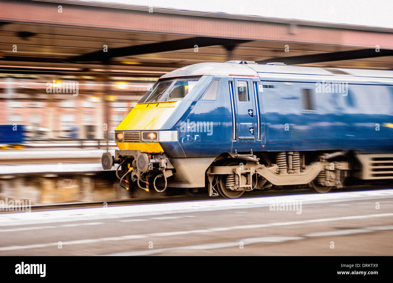 Train racing through station Stock Photo