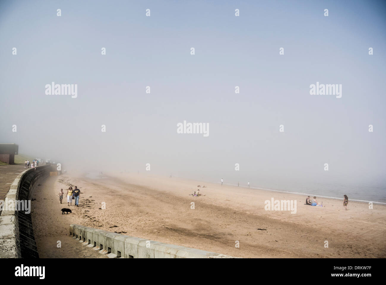 People on the beach at Whitley Bay in a summer sea fret. North Tyneside. Stock Photo