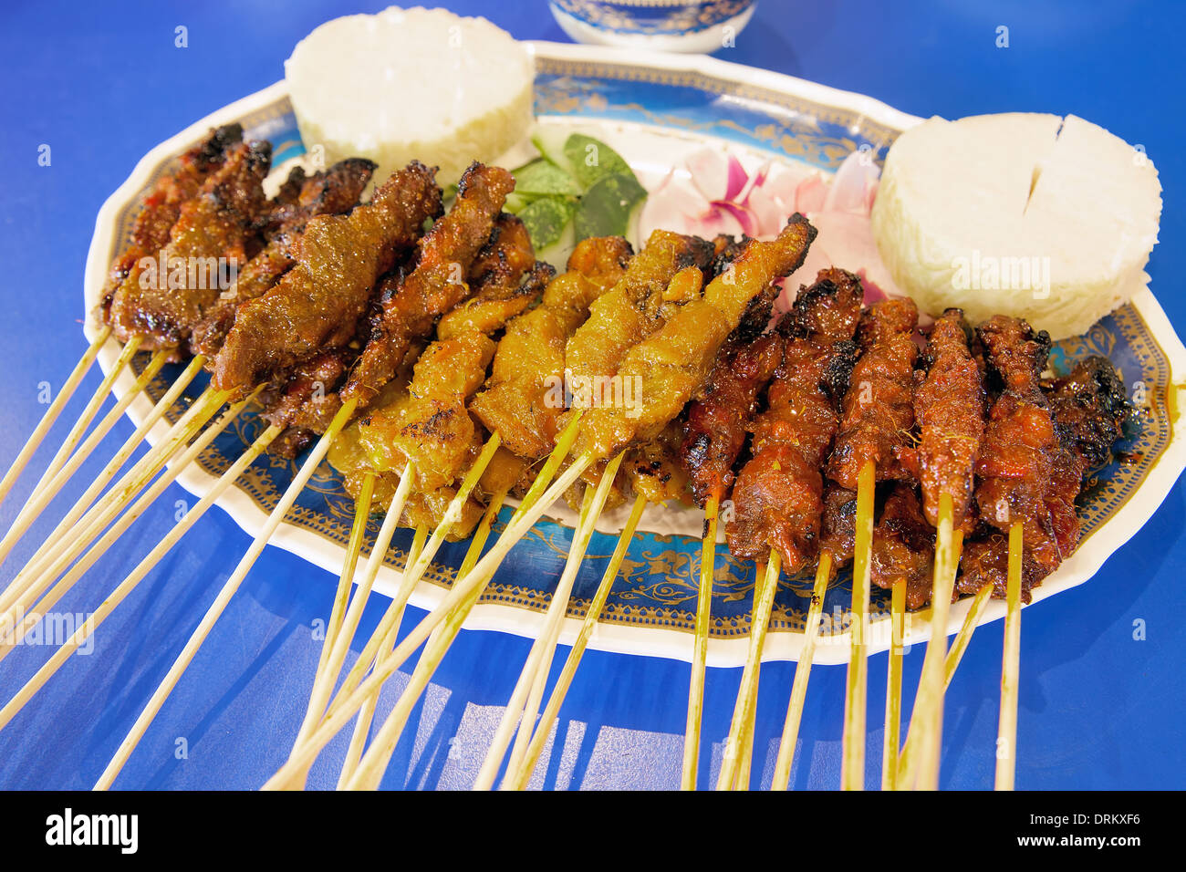 Satay Chicken Beef and Mutton with Cucumbers Onions and Rice Cake Stock Photo