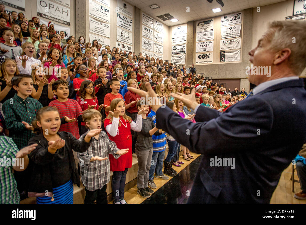 A music teacher directs multiracial middle school children singing ...