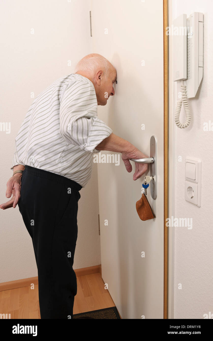 Old man looking through peephole of apartment door Stock Photo