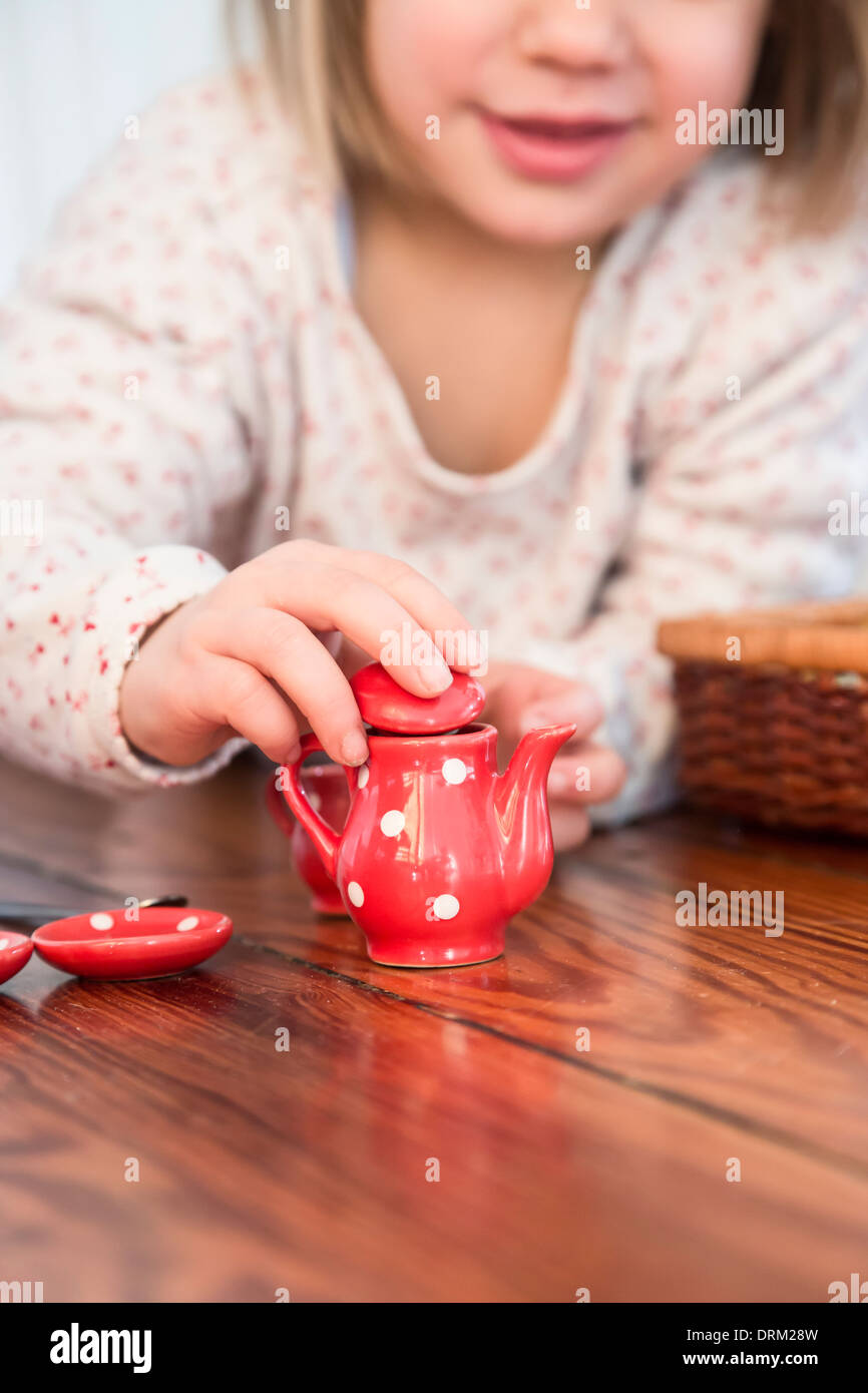 Little girl playing with dolls china set Stock Photo