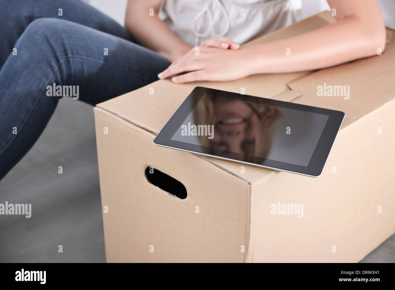 Young woman with cardboard box and tablet computer Stock Photo