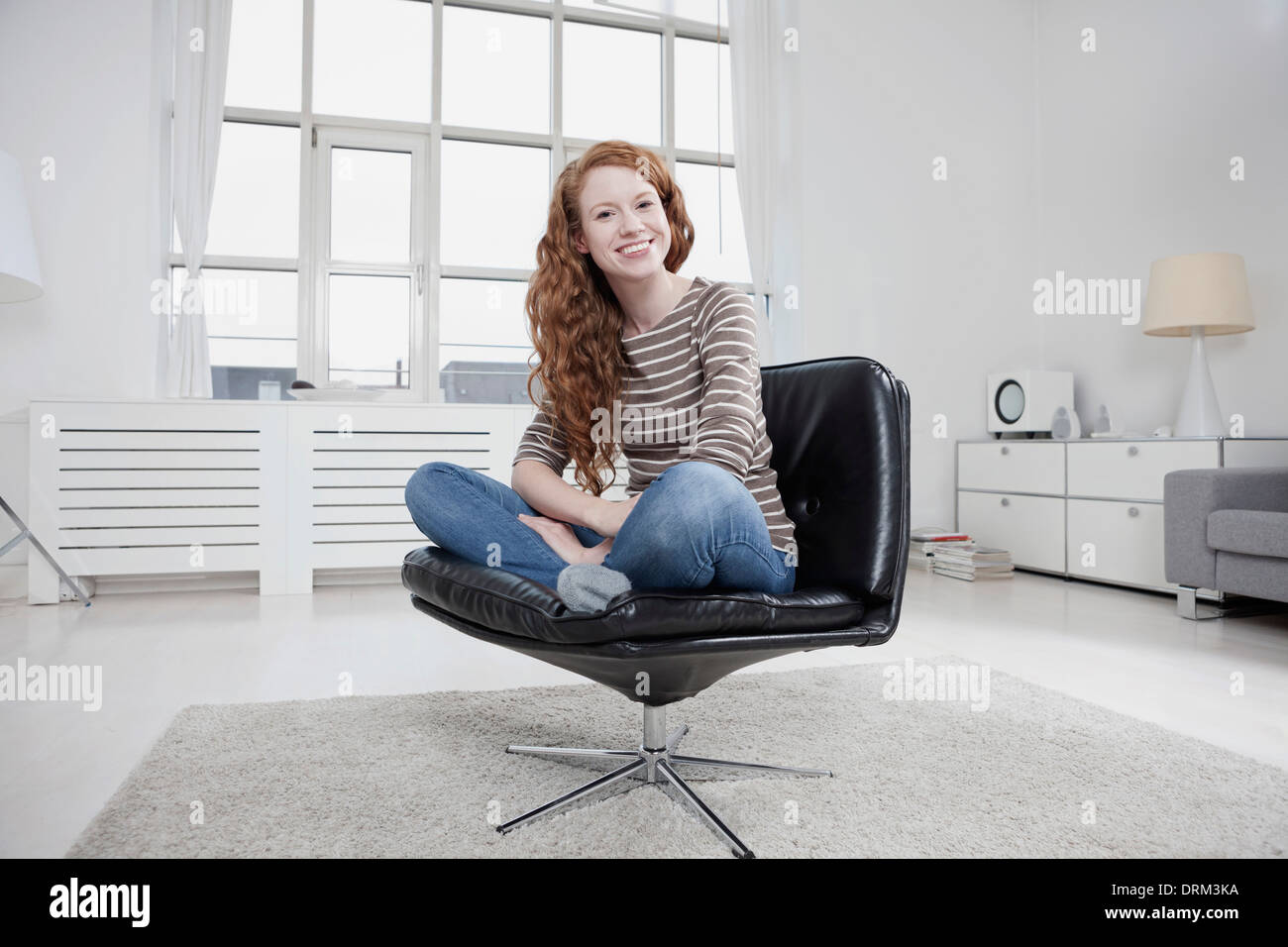 Germany, Munich, Woman at home, sitting in chair cross
