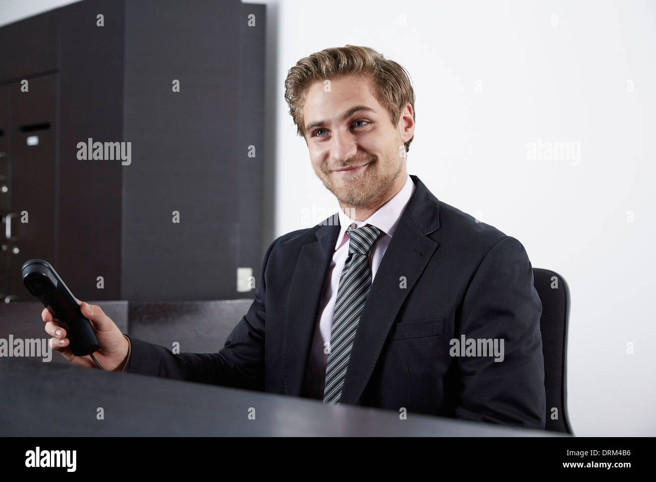 Germany, Neuss, Receptionist holding receiver Stock Photo