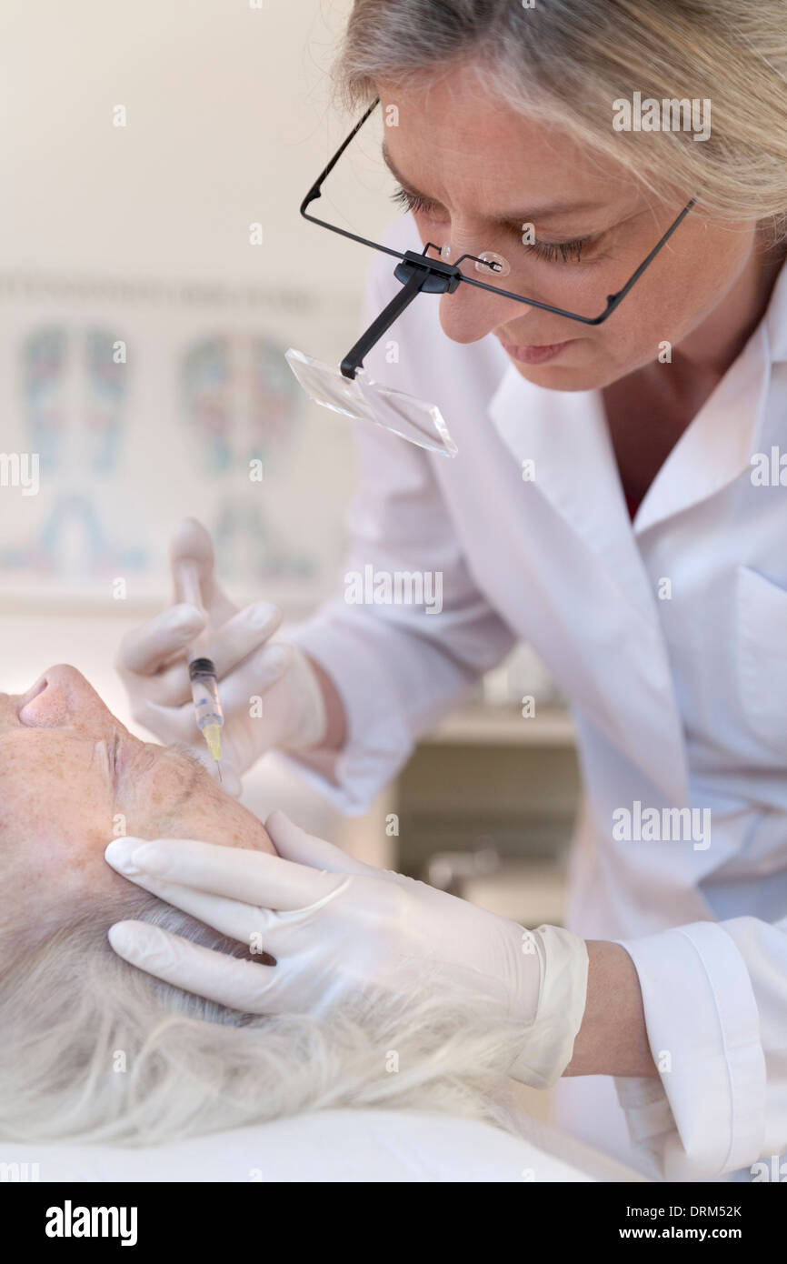 Female alternative practitioner giving senior woman injection ...