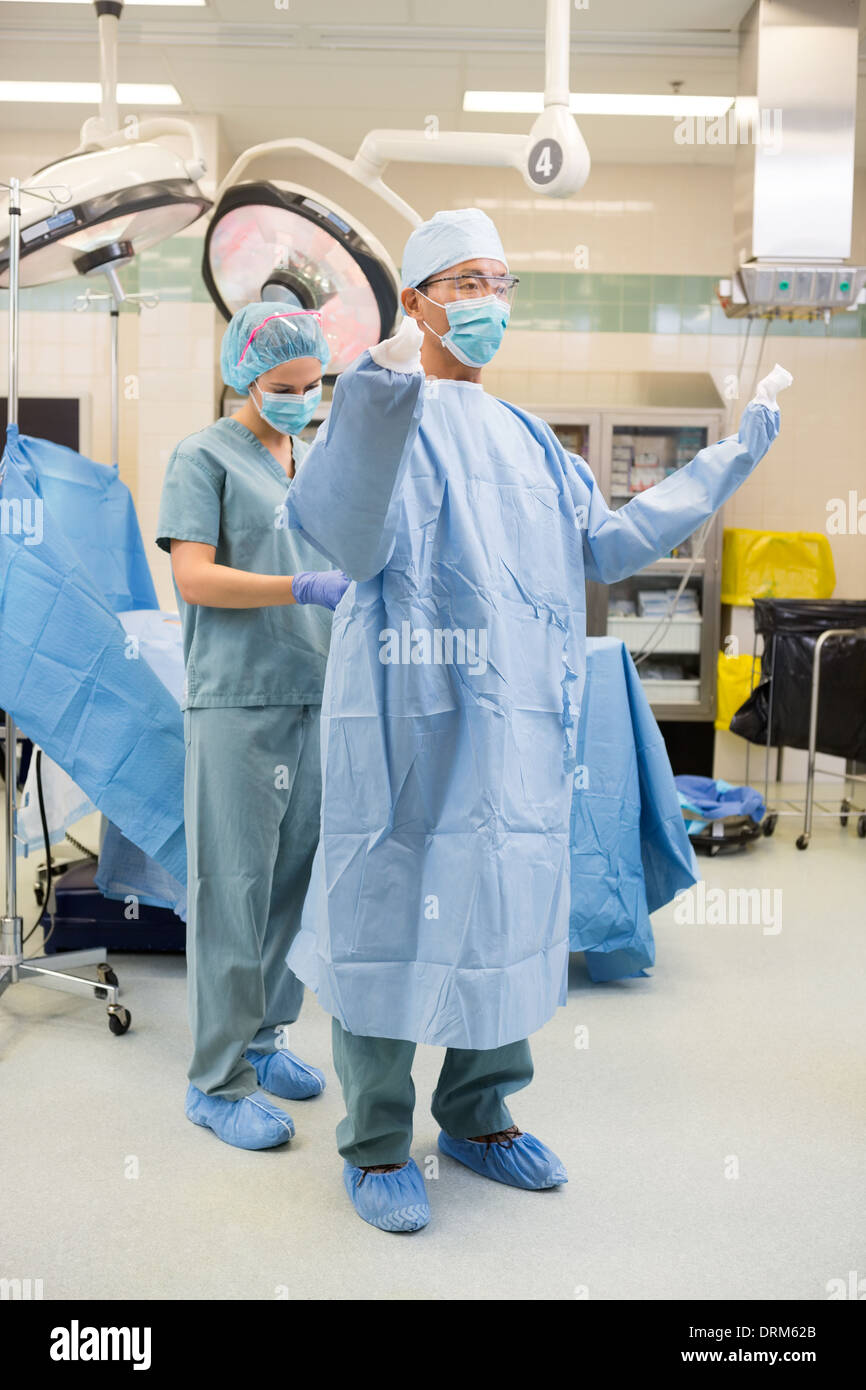 Nurse Assisting Surgeon With Sterile Gown Stock Photo