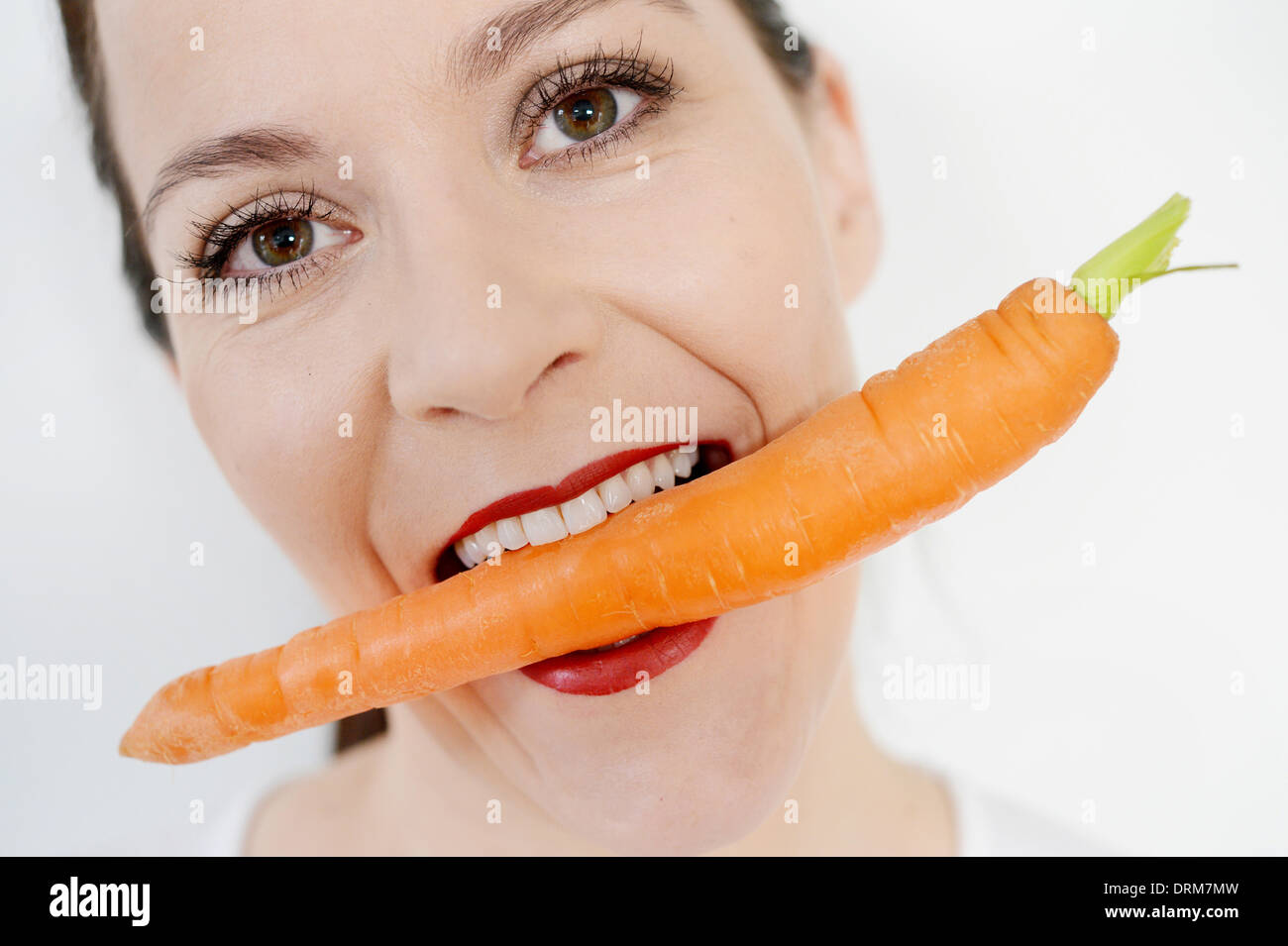 A woman biting symbolically in a carrot Stock Photo Alamy