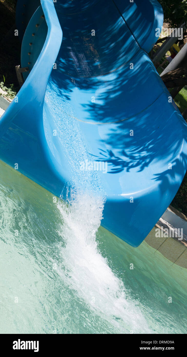 Water puring from end of slide chute waterpark hot sunny fun Stock Photo