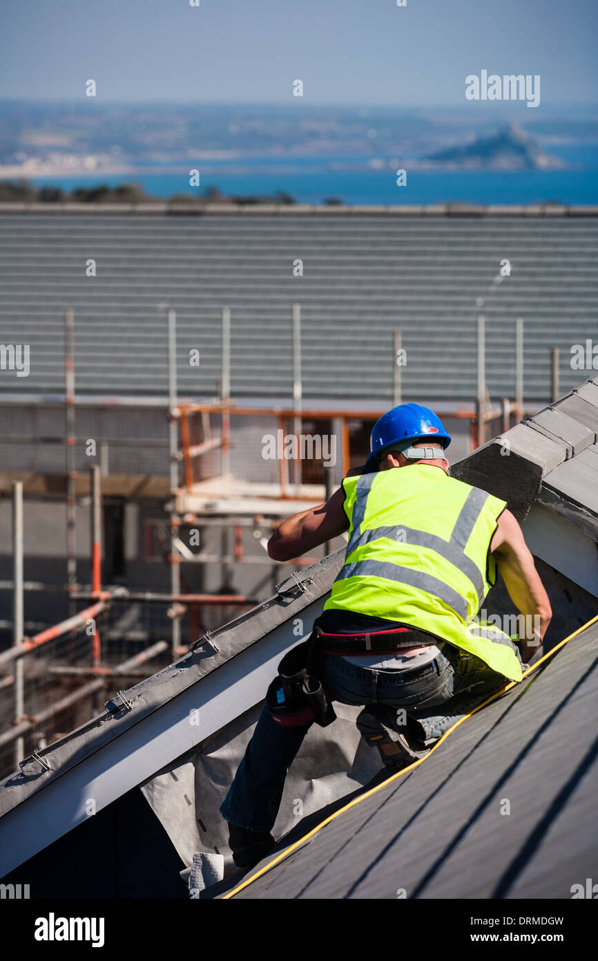 A construction worker on the roof of a new build house in a rural housing development, Madron, Cornwall, UK Stock Photo