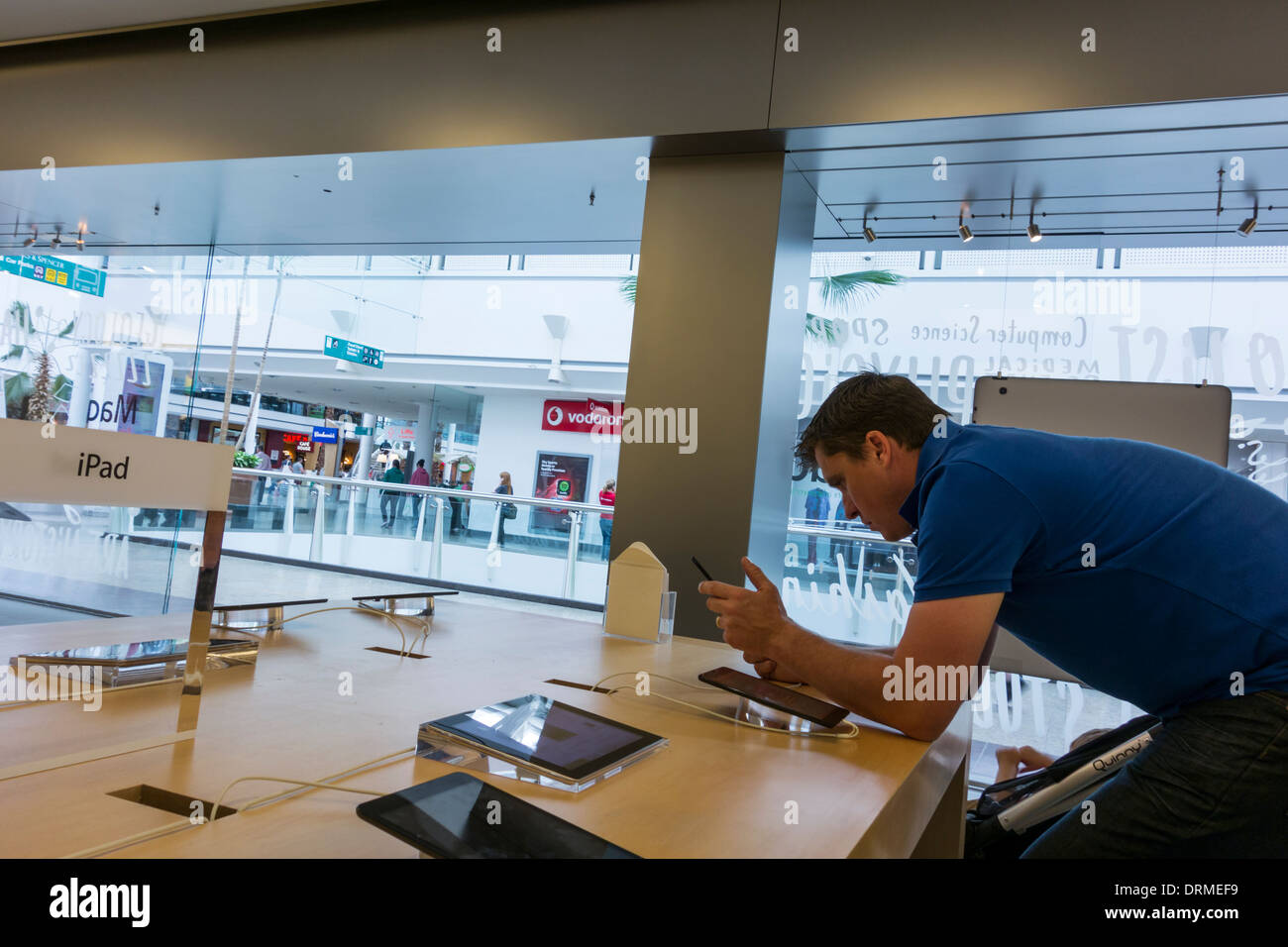 A young man using a iPad in Apple Store in The Mall at Cribbs Causeway, Bristol, UK Stock Photo