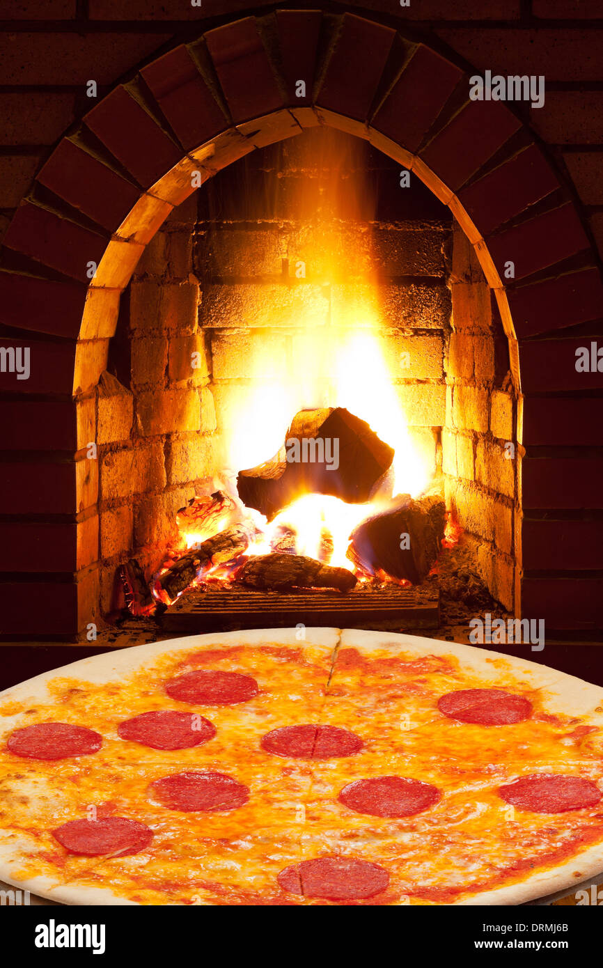 Italian Pizza With Sausage And Open Fire In Wood Burning Oven