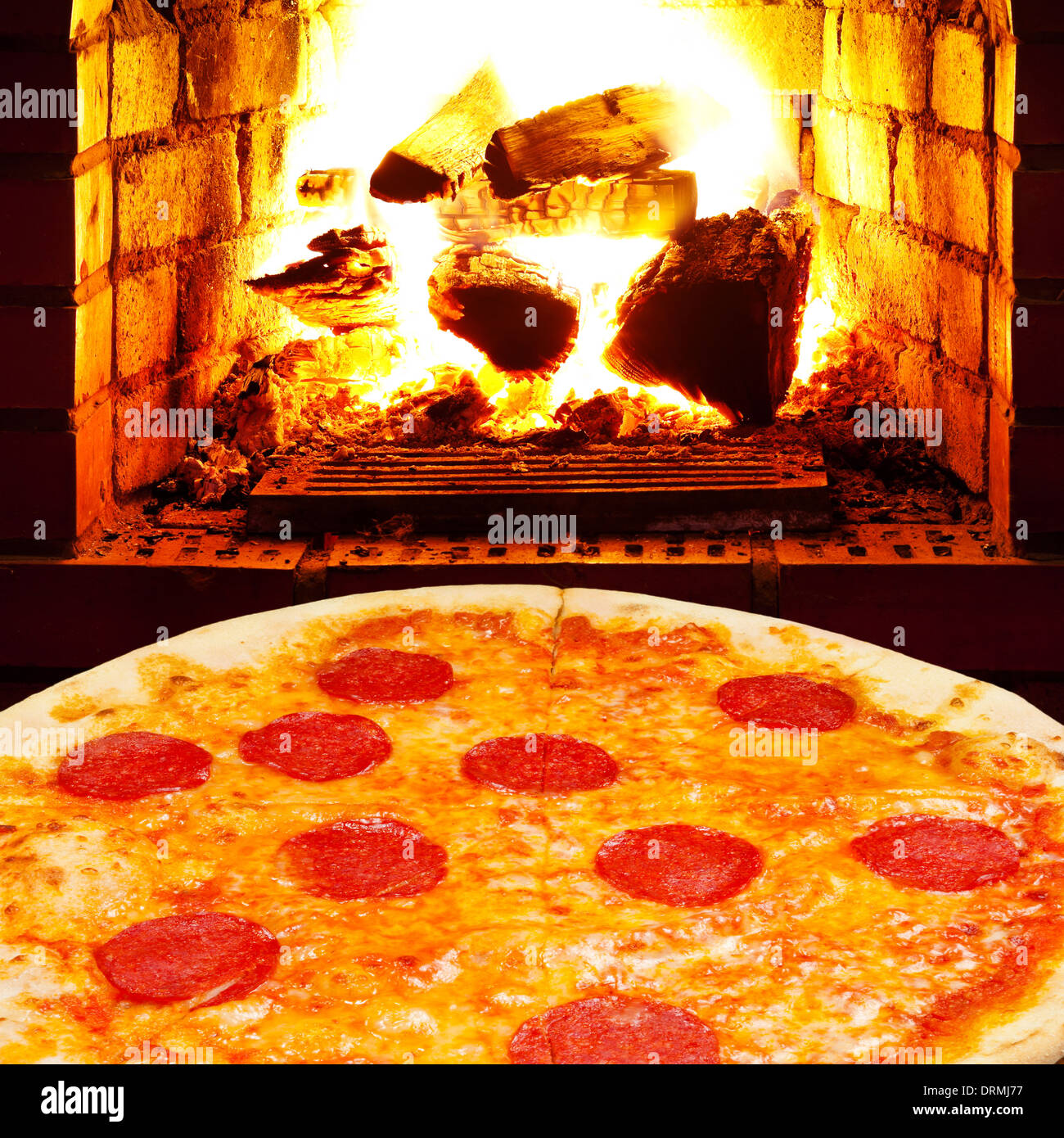 italian pizza with salami and open fire in wood burning stove Stock Photo