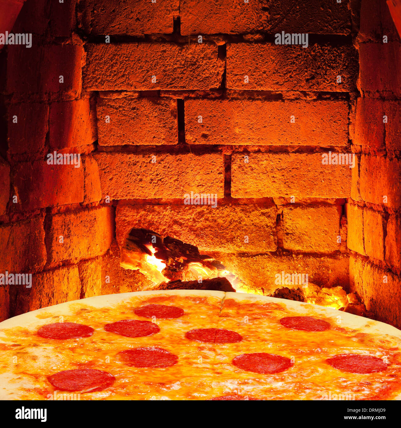 italian pizza with salami and hot brick wall of wood burning oven Stock Photo