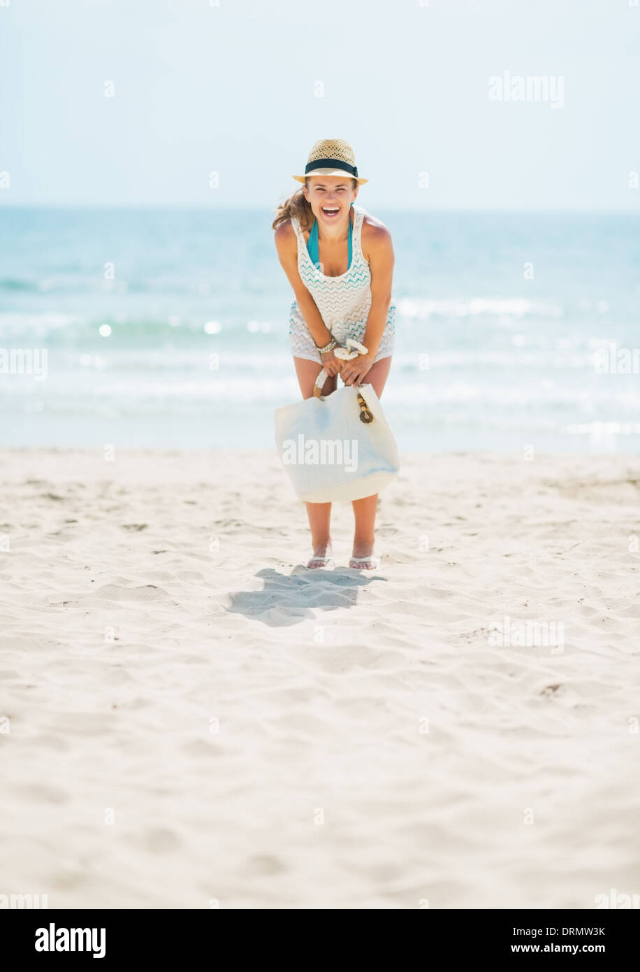 Full length portrait of young woman in hat and with bag having fun time ...