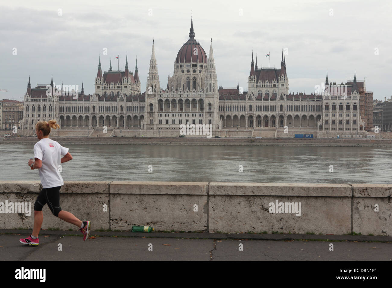 A woman runs along the embankment of the Danube with Hungarian Parliament Building seen in the background in Budapest, Hungary. Stock Photo