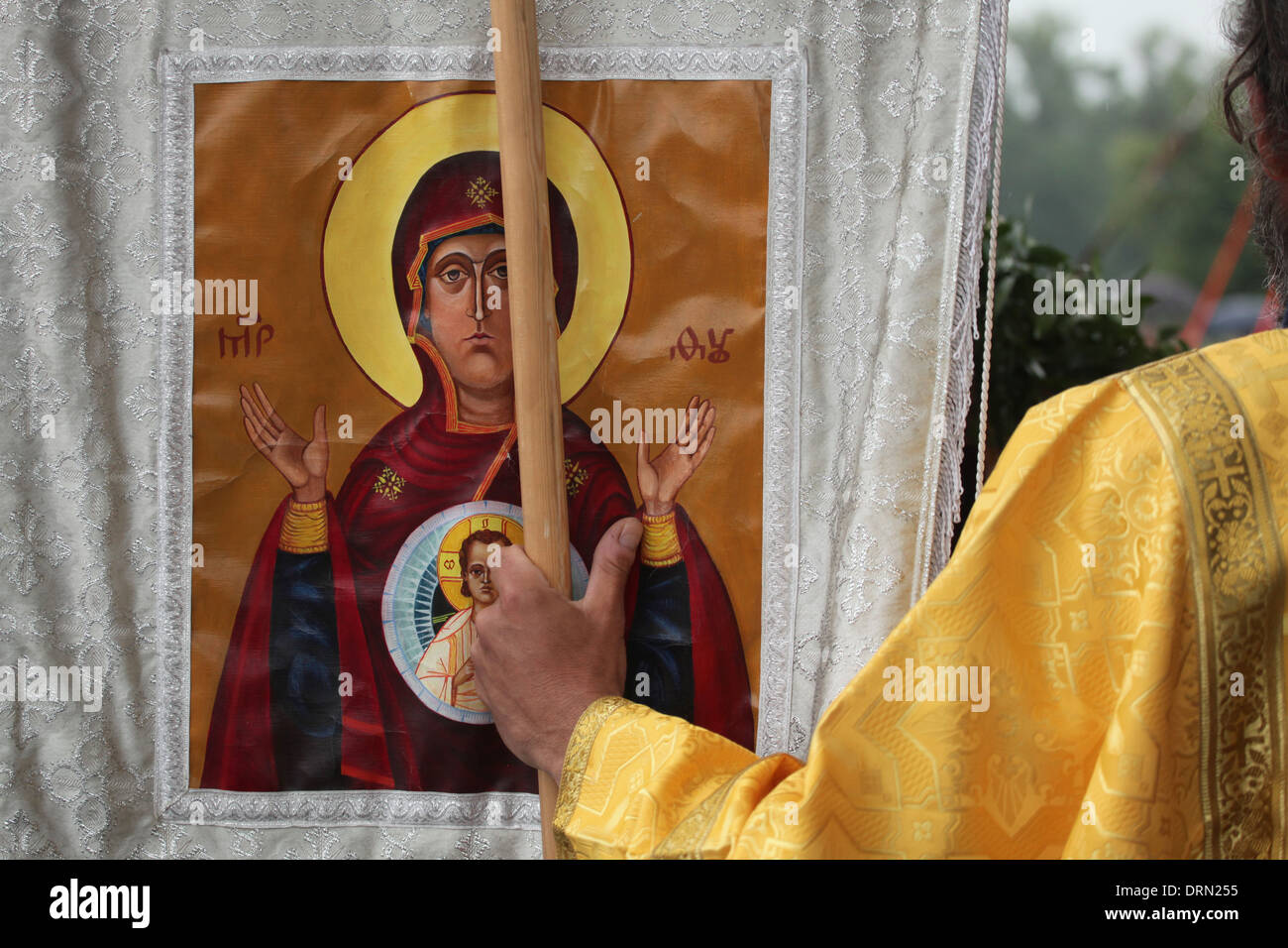 Orthodox priest holds the khorugv decorated with an icon of the Virgin during an orthodox service. Stock Photo