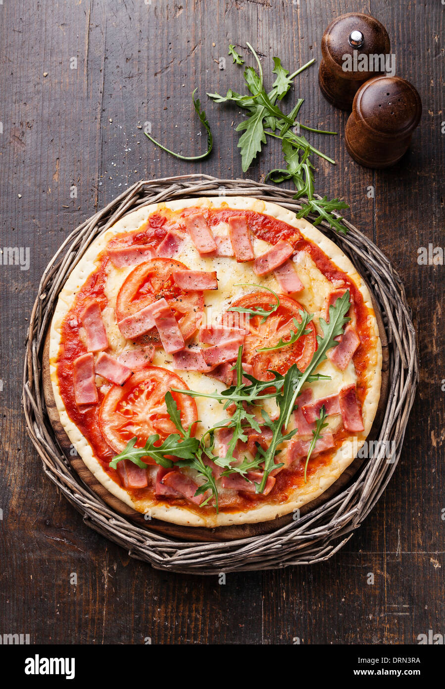 Italian pizza with ham and arugula leaves on wooden table Stock Photo