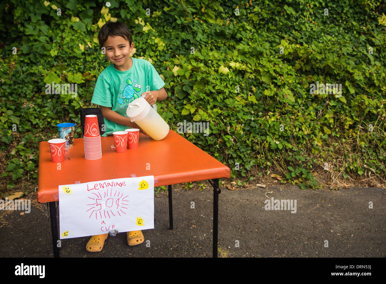 Boy pouring lemonade in cup, child's lemonade stand, Astoria, Oregon, USA Stock Photo