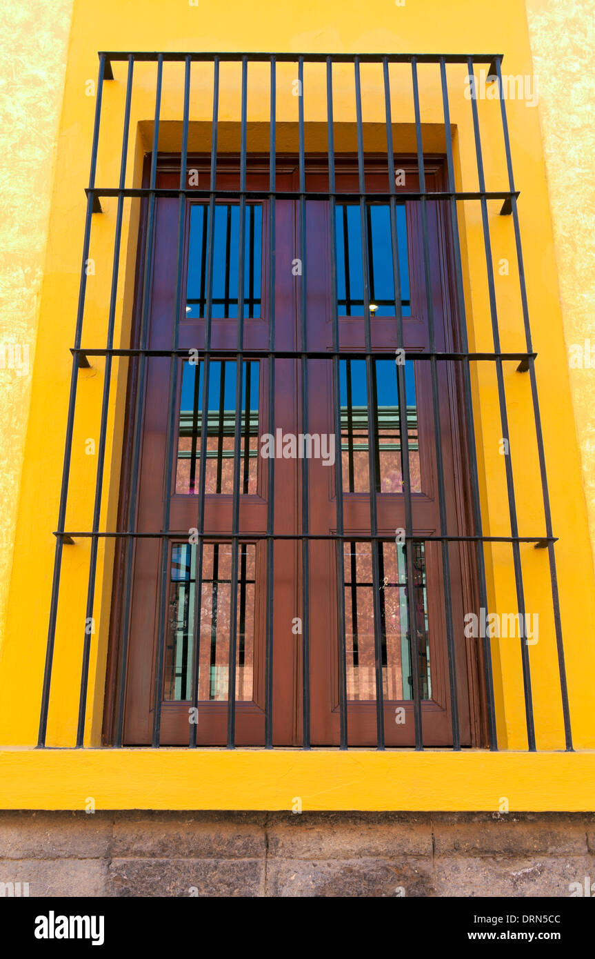 Window opening with reflections on panes surrounded by protective bars and colorful frame Stock Photo