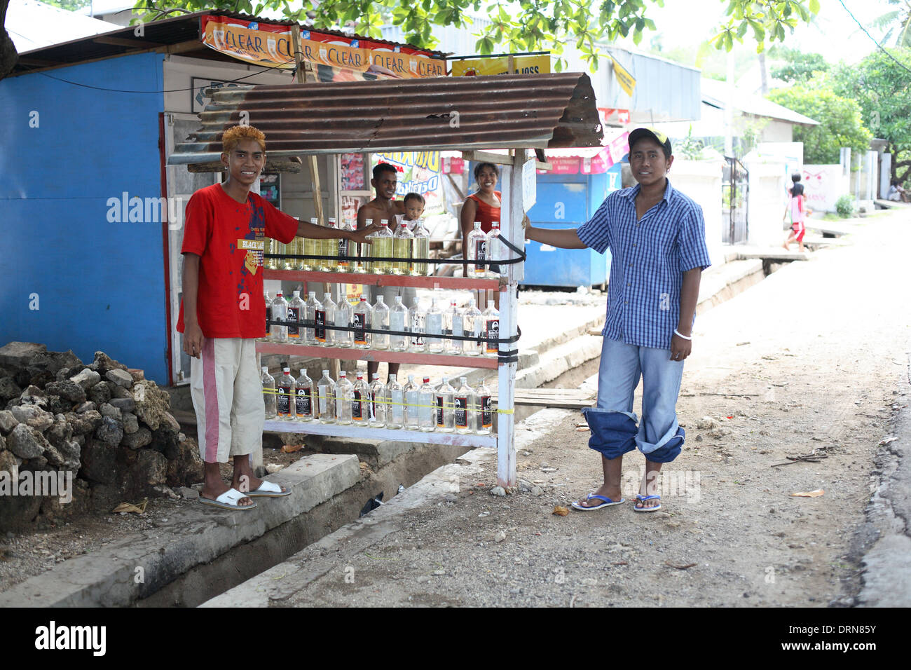 Smiling young men sell gasoline / petrol in bottles along the side of the road. Kupang, West Timor, Indonesia Stock Photo
