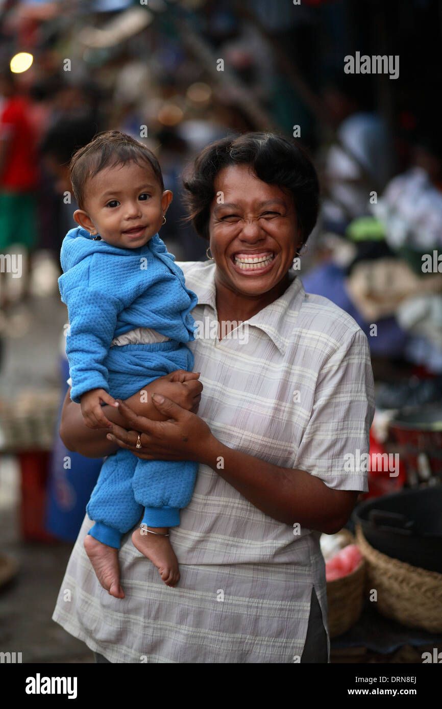 Portrait of smiling woman holding a smiling girl looking at camera with out of focus background. Kupang, West Timor, Indonesia Stock Photo