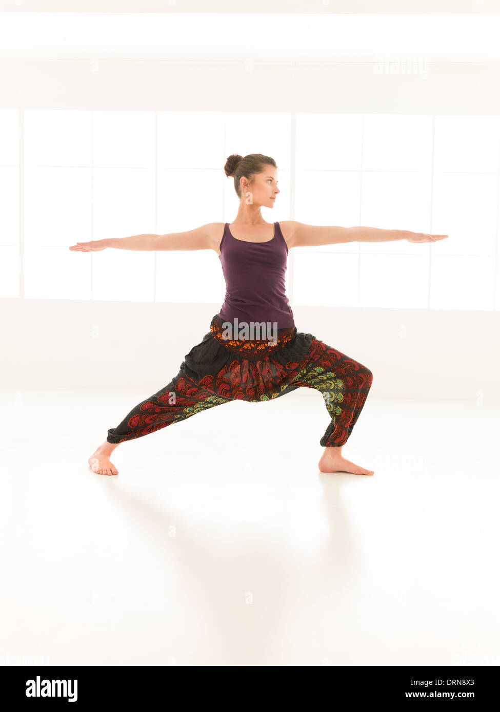 single young, woman in yoga pose, dressed colorful in studio light and reflection Stock Photo