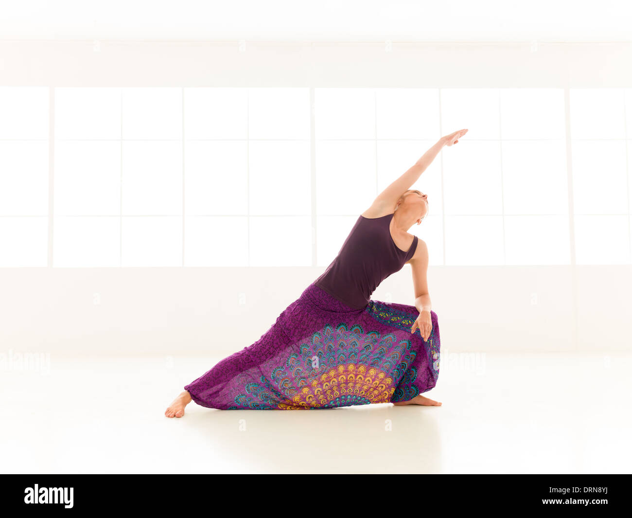 full body view of young slim woman in yoga posture, dressed icolorful indor studio Stock Photo