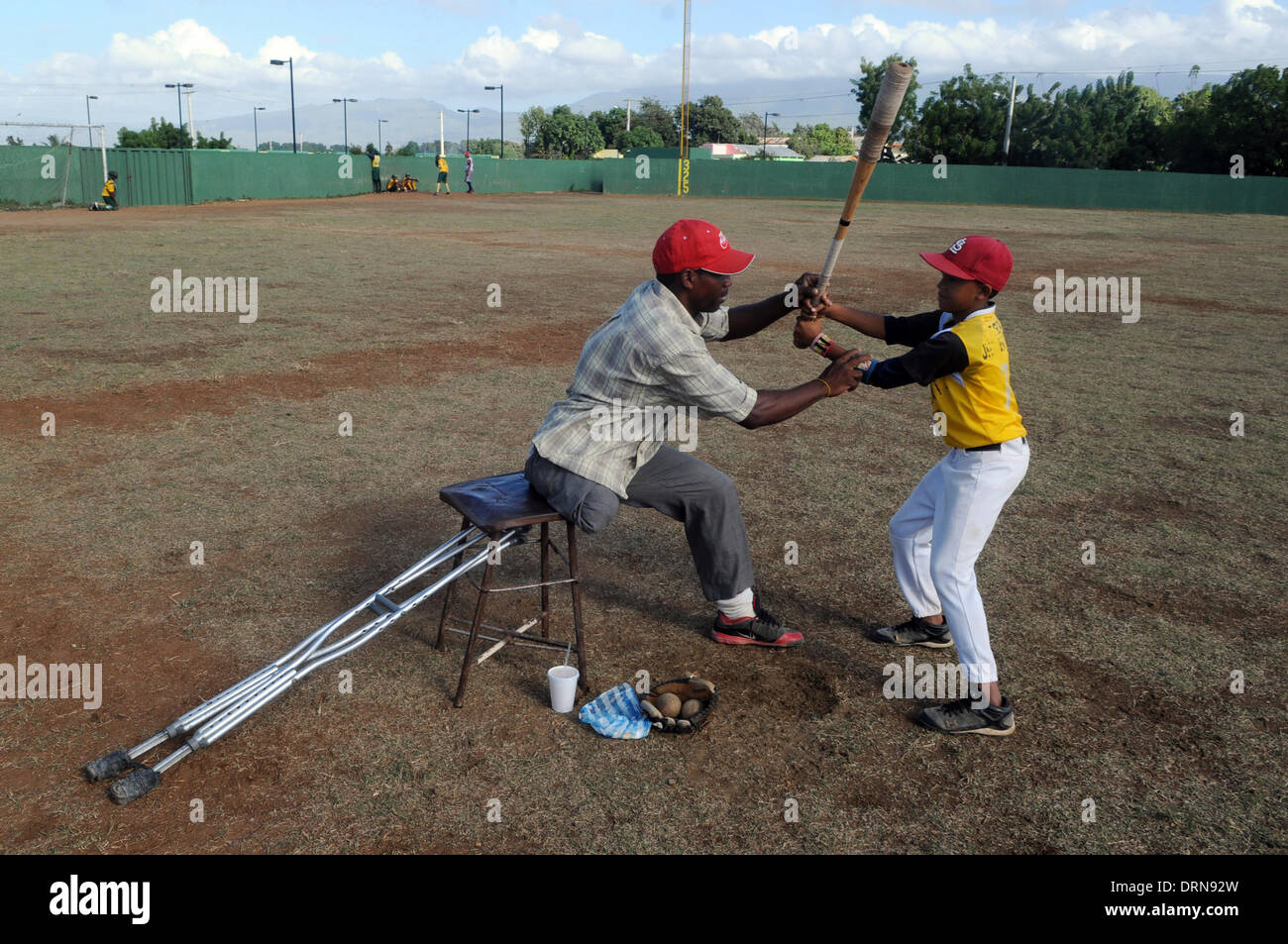 Santiago, Dominican Republic. 30th Jan, 2014. Pedro Sanchez (L), 37 years old, teaches a kid baseball in Santiago city, Dominican Republic, on Jan. 29, 2014. Sanchez lost his right leg in a car accident. According to a study from the World Health Organization (WHO), Dominican Republic holds the biggest worldwide mortality rates in car accidents, with 41.7 deaths for every 100,000 residents. Due to the high mortality related to car accidents, the winning players of the world baseball classic has begun a campaign, according to local press. © Onelio Dom¨ªnguez/Xinhua/Alamy Live News Stock Photo