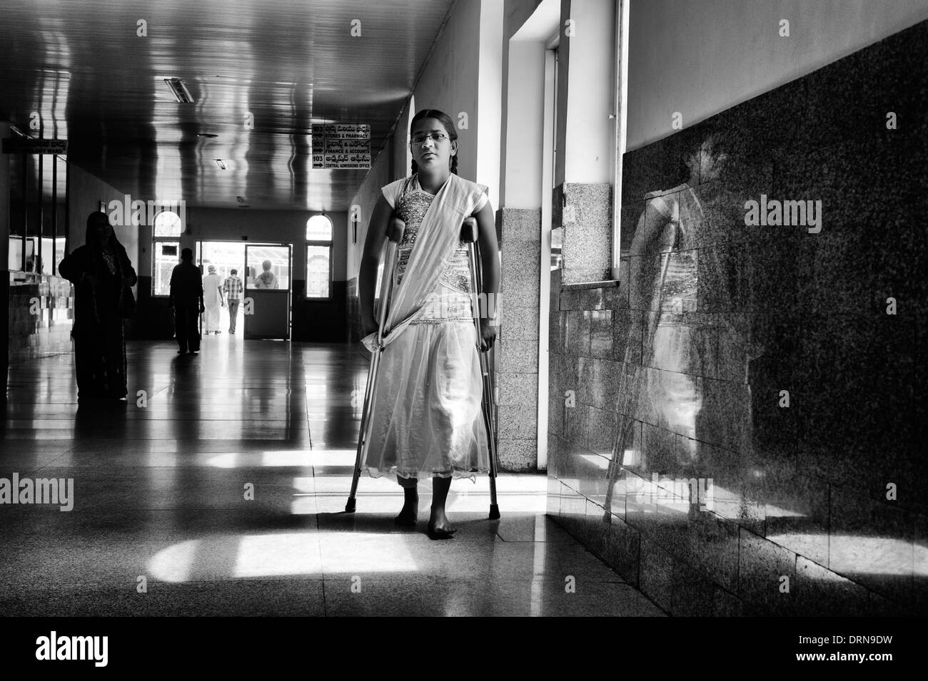 Indian girl patient walking with crutches in the Super Speciality hospital, Puttaparthi,  Andhra Pradesh, India. Monochrome Stock Photo
