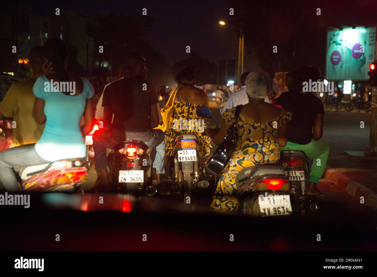 people riding scooters and mopeds at night in Bobo Dioulasso, Burkina Faso Stock Photo