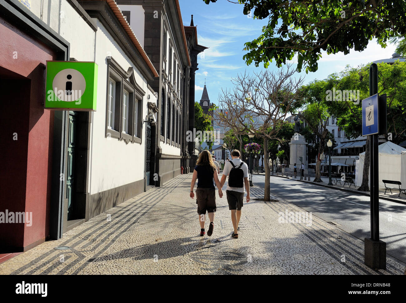Funchal Madeira A young couple walk hand in hand past a tourist information point Stock Photo