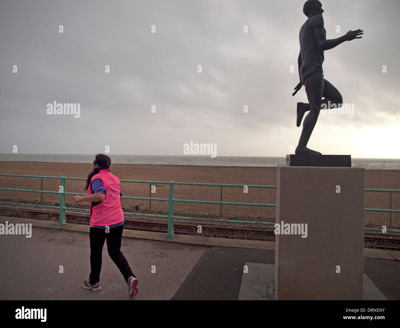 A jogger on the Brighton seafront runs past the statue of Steve Ovett Stock Photo