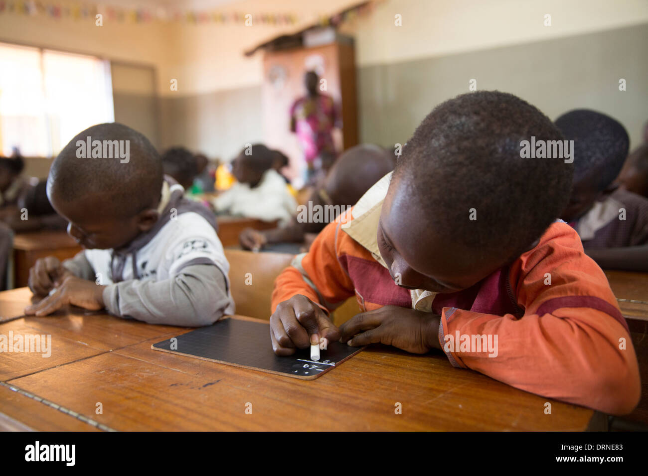young boys writing in chalk on blackboard in classroom of church supported school in Bobo Dioulasso, Burkina Faso, Africa Stock Photo