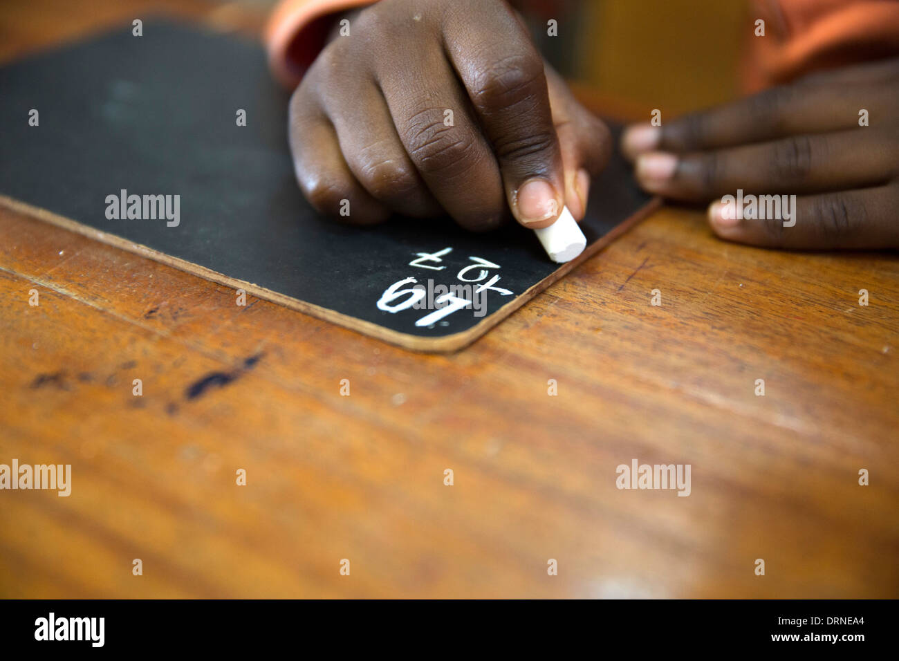 young boy writing in chalk on blackboard in classroom of church supported school in Bobo Dioulasso, Burkina Faso, Africa Stock Photo