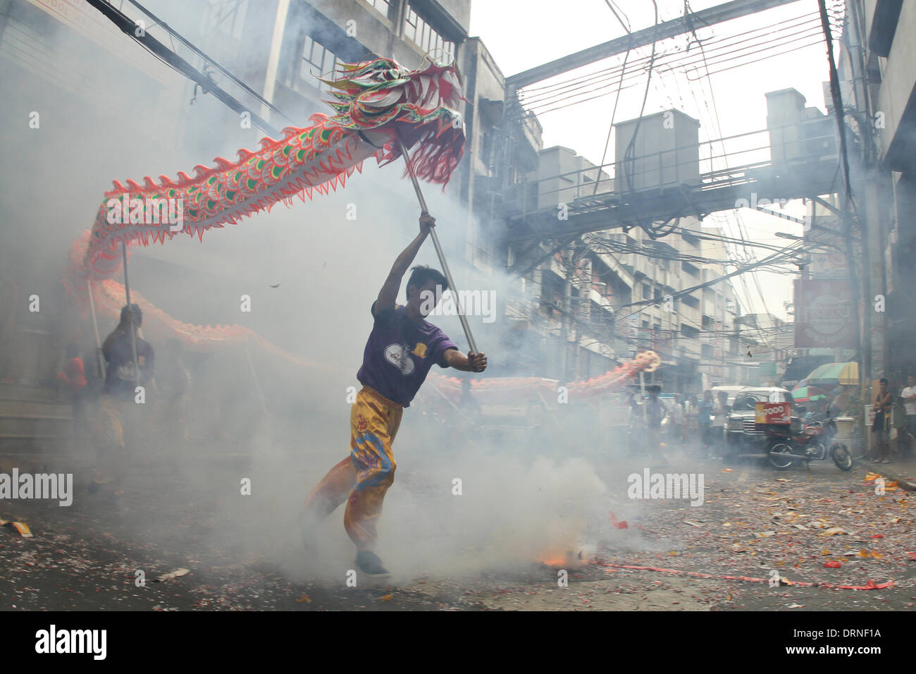 Manila, Phillipines. 30th January 2014. Street performers carry their dragon around firecrackers in Chinatown Manila a day before the Chinese New Year on January 30, 2014. Lucky charms, fruits, street performers and firecrackers were seen around Chinatown in Manila, a day before the celebration of the Chinese New Year, the Year of the Horse. Photo by Mark Cristino/Alamy Live News Stock Photo