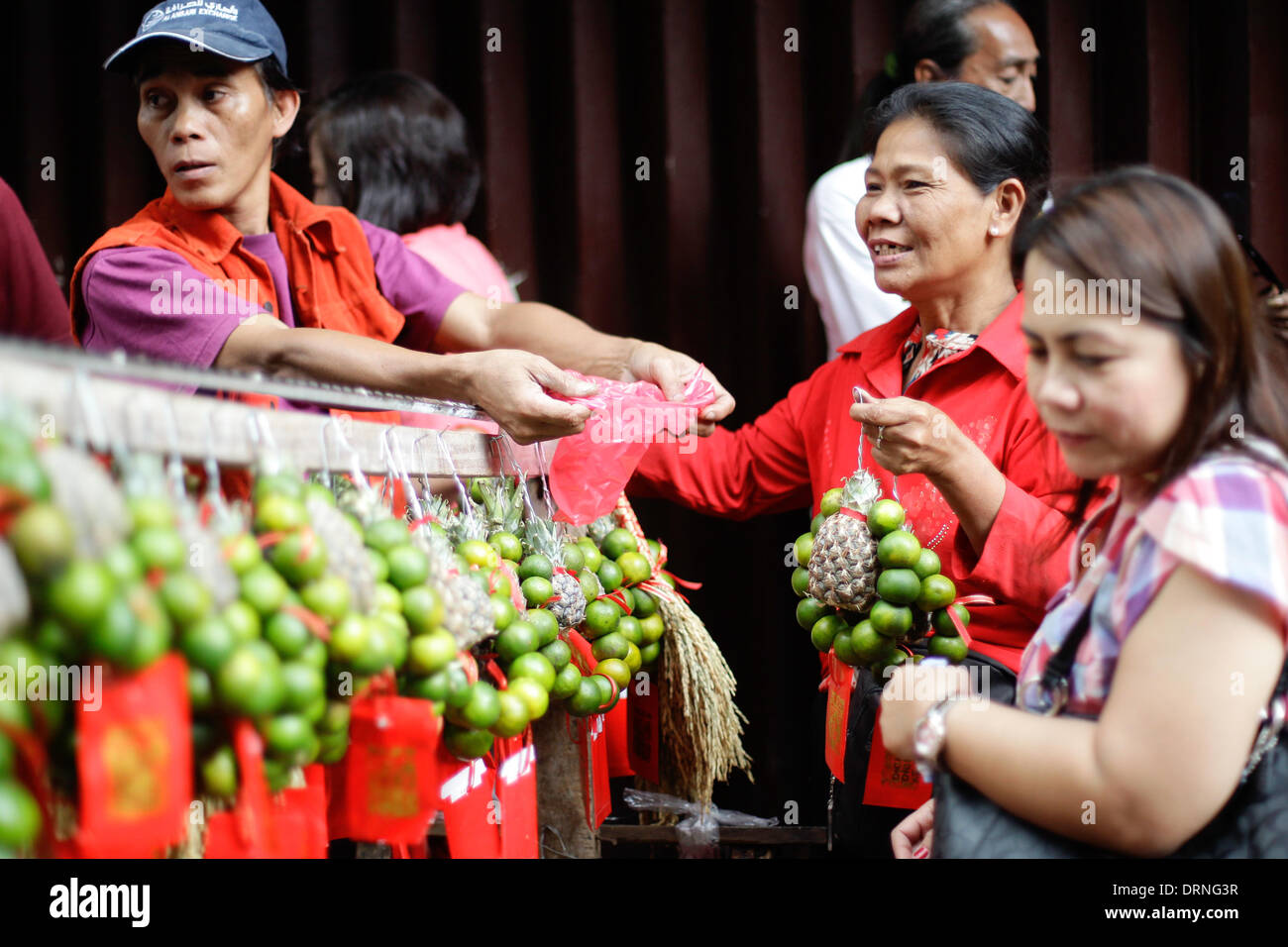 Manila, Phillipines. 30th January 2014. A woman purchases round fruits from a street vendor in Chinatown Manila on January 30, 2014. Lucky charms, fruits, street performers and firecrackers were seen around Chinatown in Manila, a day before the celebration of the Chinese New Year, the Year of the Horse. Photo by Mark Cristino/Alamy Live News Stock Photo