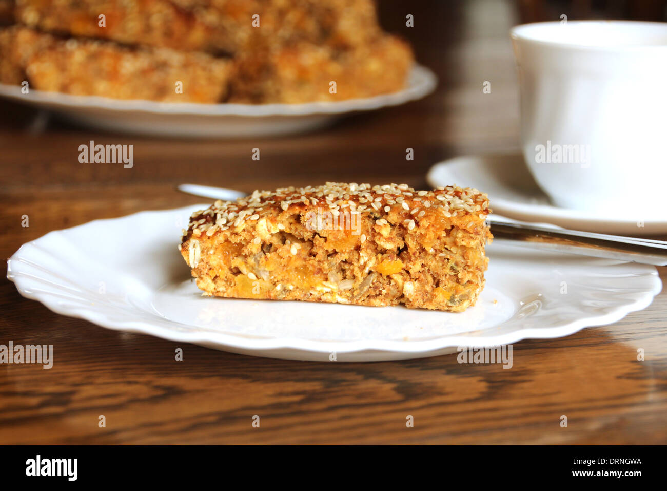 cereal bar'   breakfast , tray bake, white plate cup and saucer, 'with oats, apricot, sesame seeds and sunflower seeds Stock Photo