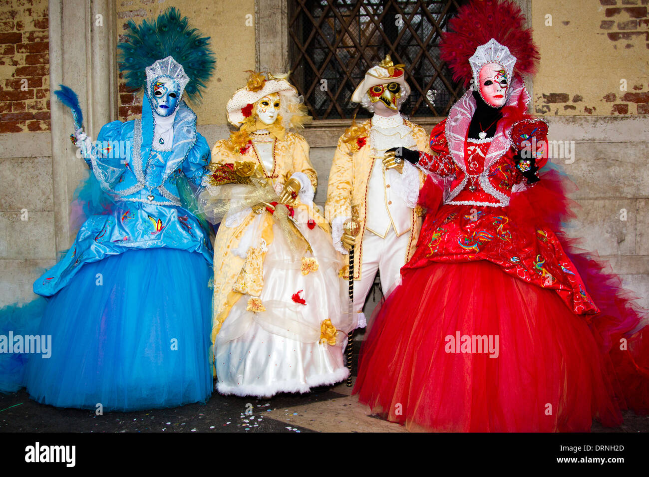 Three Costumed female in various coloured dresses and one male at the Venice carnival in St. Marks Square. Stock Photo