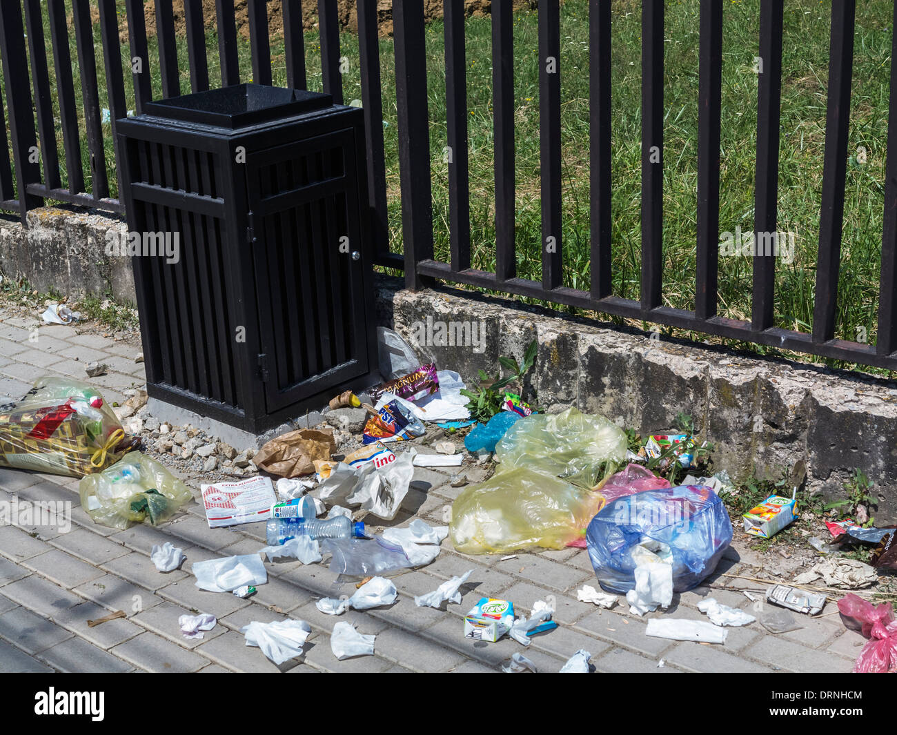 Rubbish on the street next to an empty trash can Stock Photo