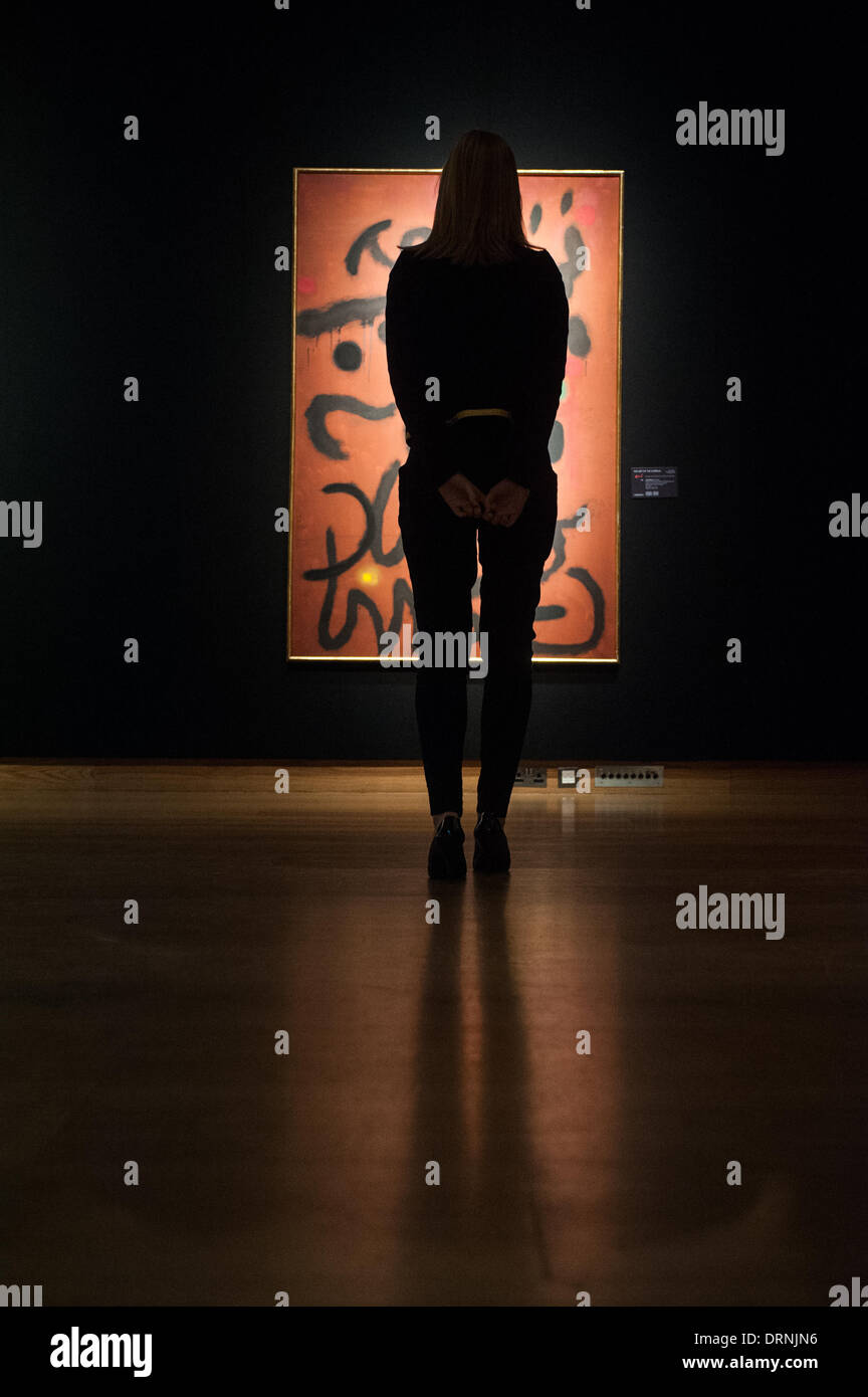 London, UK - 30 January 2014: a staff member poses in front of 'Ecriture sur fond rouge, 1960' by Joan Miro that will go on sale on the 4th February at Christie’s Credit:  Piero Cruciatti/Alamy Live News Stock Photo