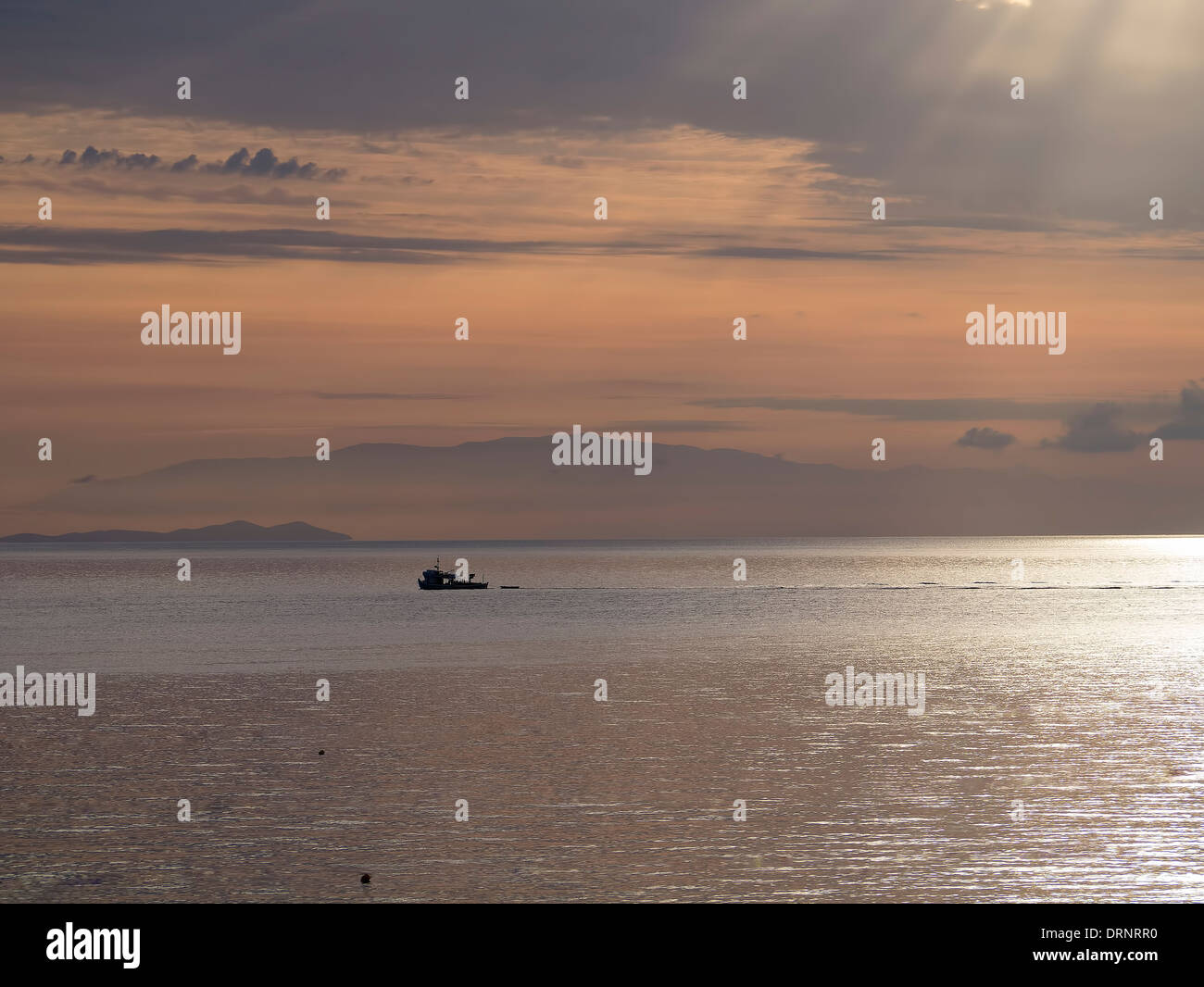 Sunrise and silhouette of a fishing boat in Greece Stock Photo