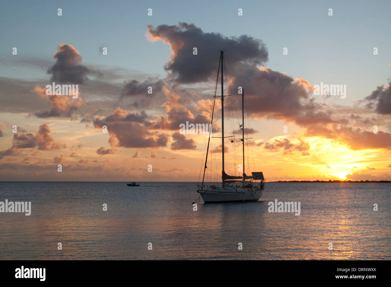 Yacht at anchor at sunset in Bonaire. The island of Klein Bonaire can be seen in the distance. Stock Photo