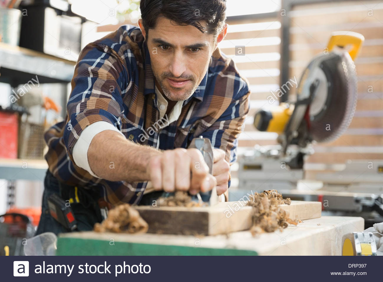 Carpenter smoothing wood with plane in workshop Stock Photo