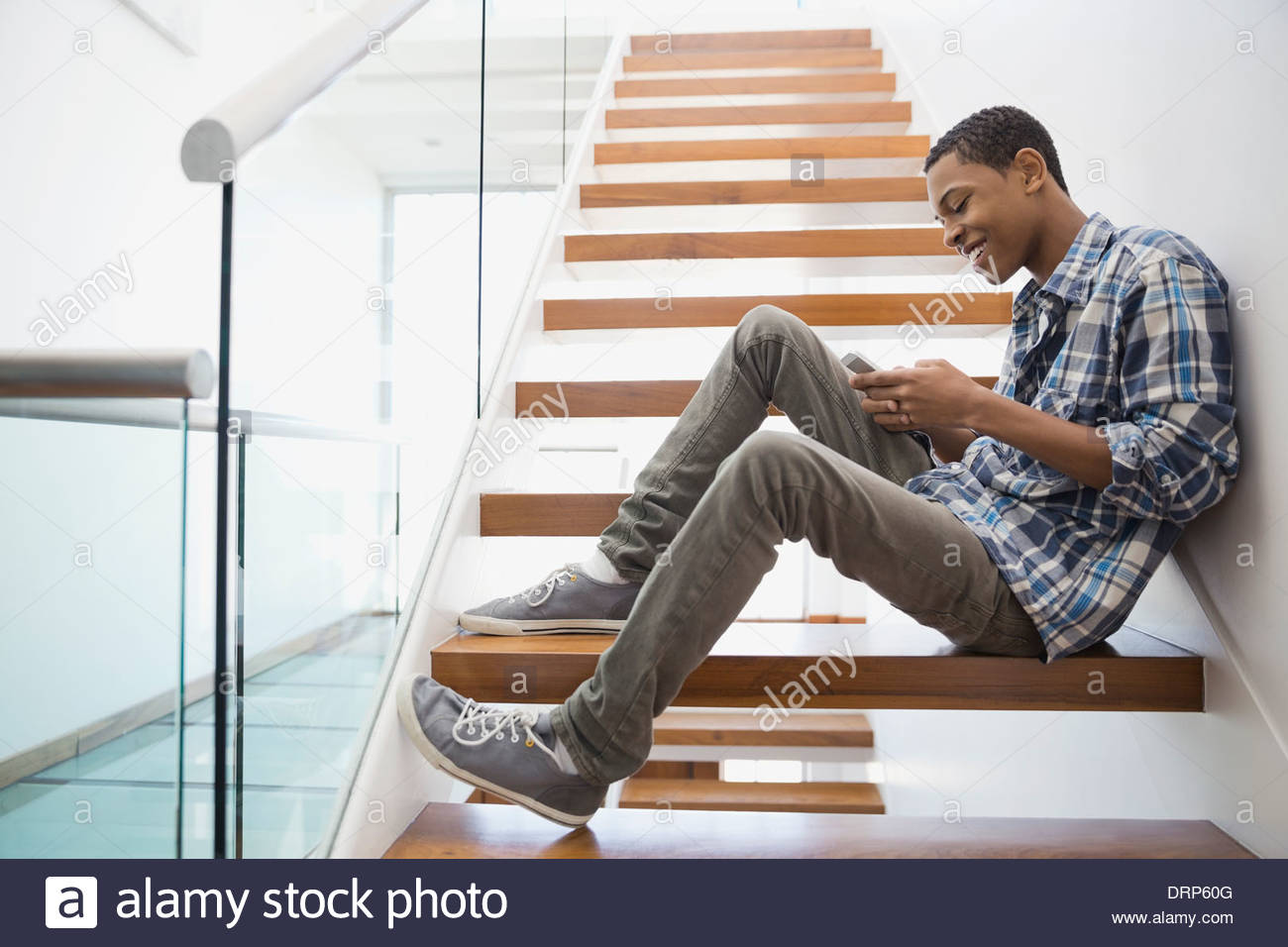 Teen text messaging on steps at home Stock Photo