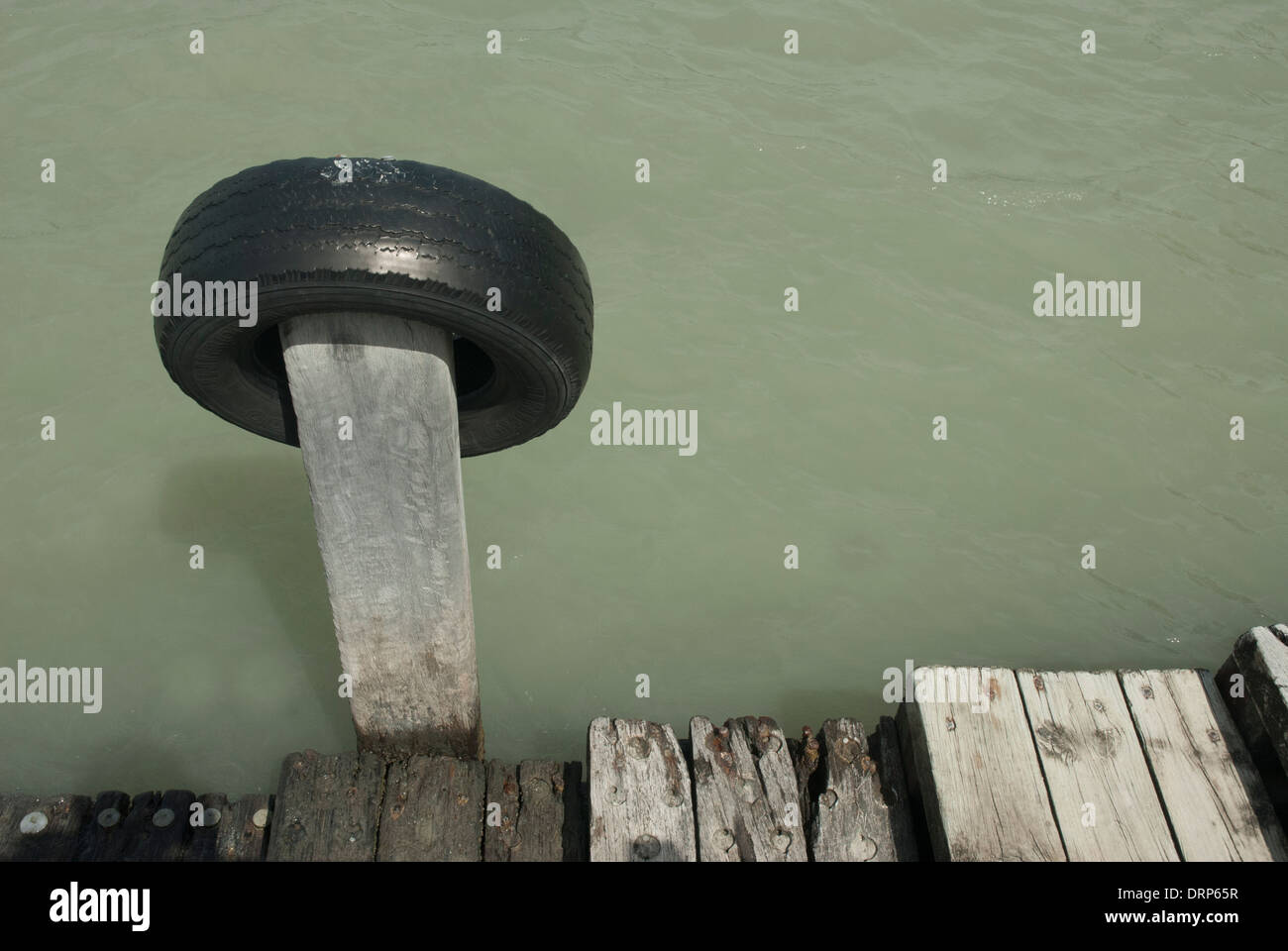 Old car tyre used as a fender on a dilapidated wooden jetty near Lyttleton, South Island, New Zealand. Stock Photo