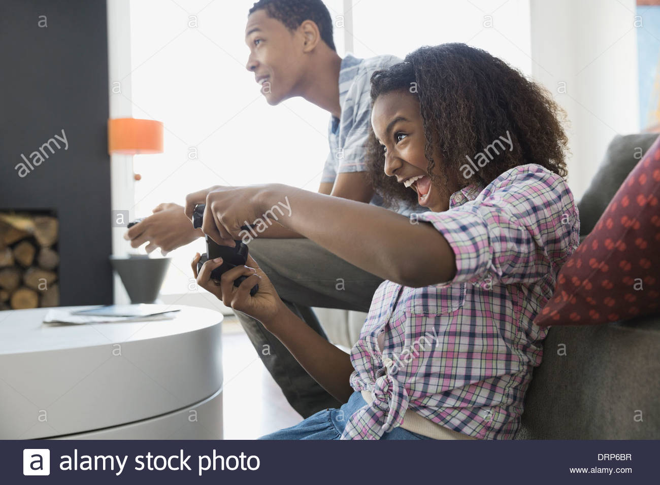 Siblings playing video games at home Stock Photo